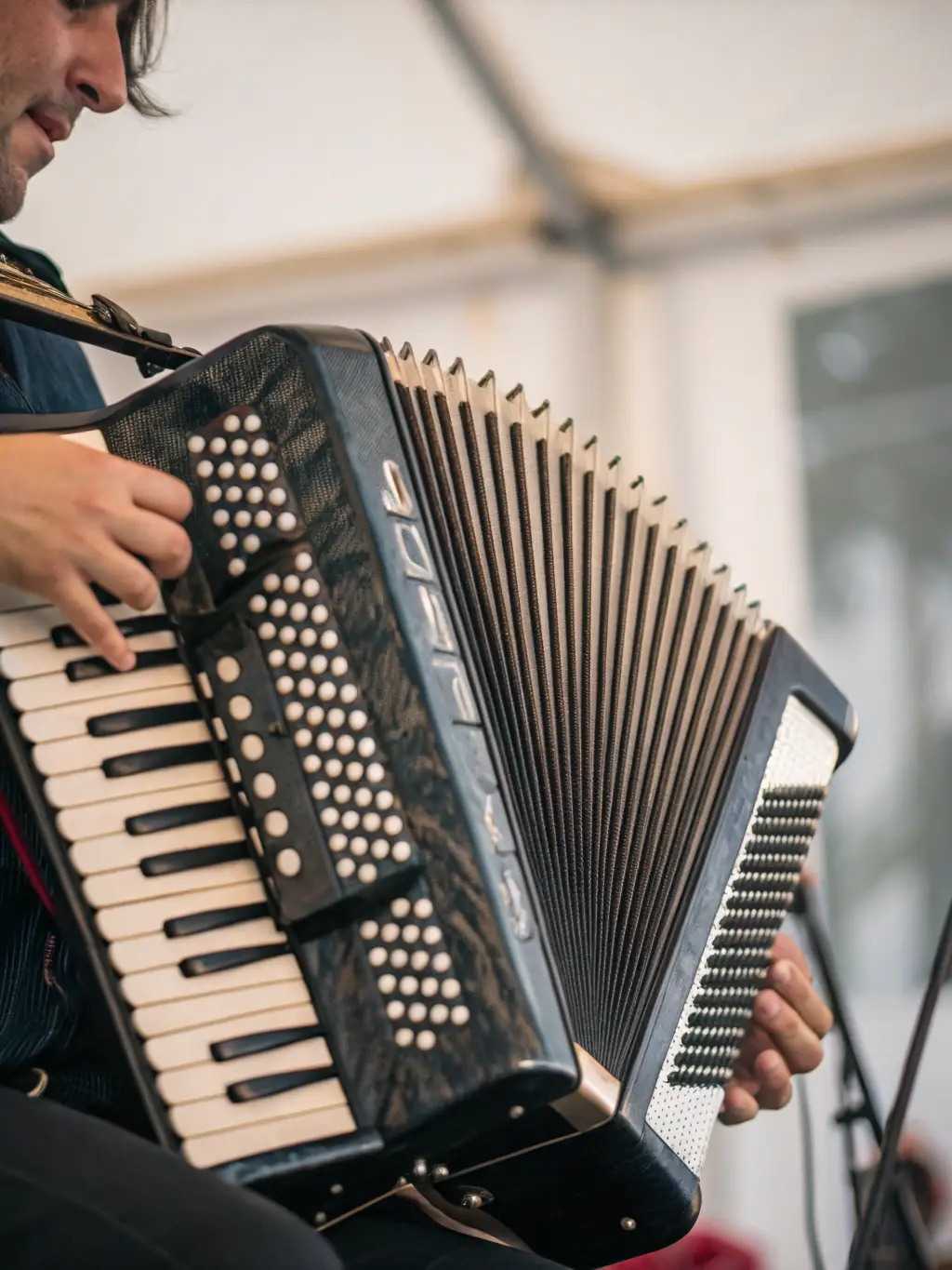 A close-up shot of a traditional Galician bagpipe (gaita) being played, with blurred background showing a lively festival scene.